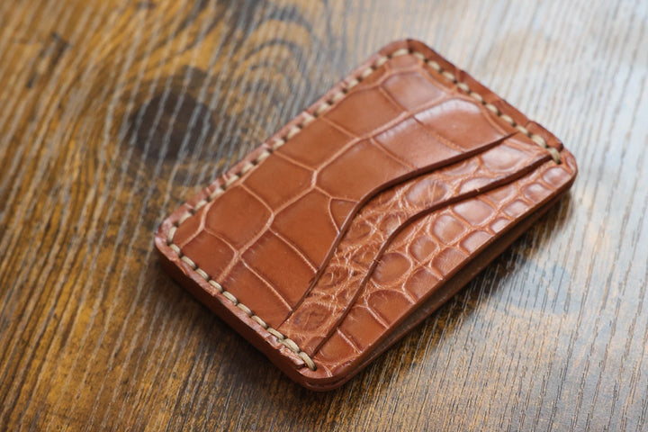 Buckler Honey American alligator card holder at an angle, showing the twin curved slots and natural-thread hand stitching