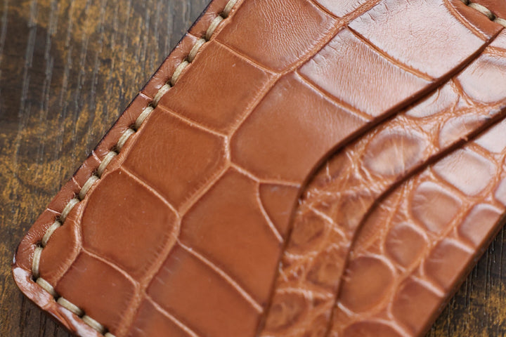 Close-up of the Buckler in Honey American alligator belly, showing the glossy belly scales and hand stitching